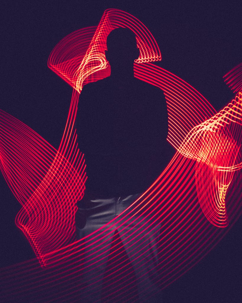 A silhouette of a person surrounded by artistic red light trails, creating a dynamic visual effect.