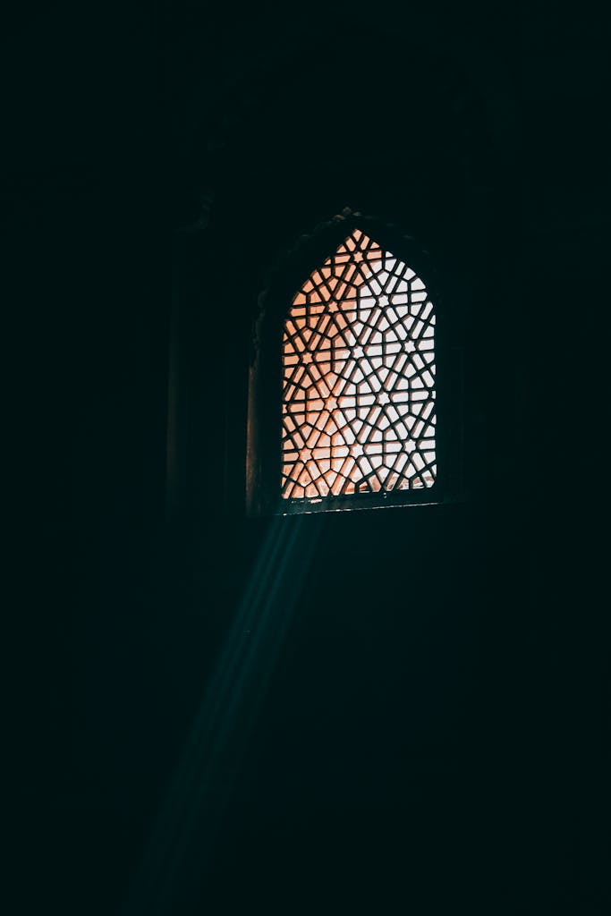 Sunlight streaming through a Mughal-style window in Agra, showcasing intricate Islamic architectural patterns.